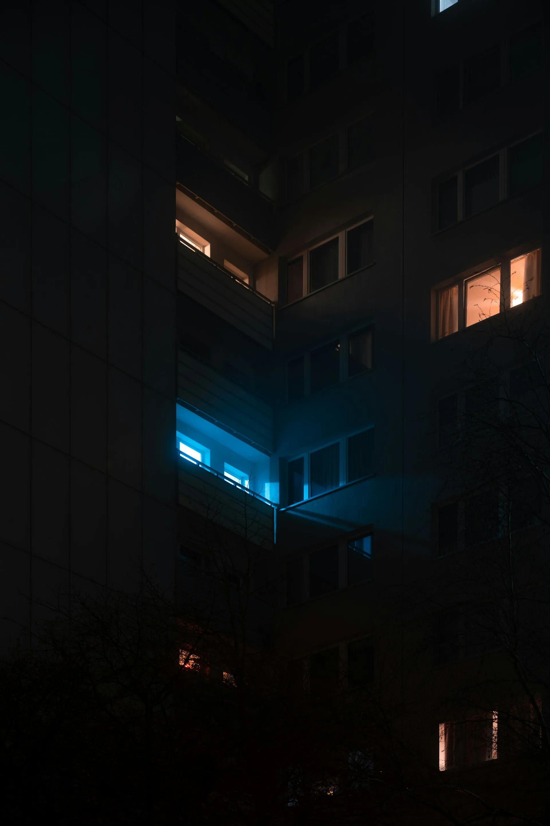 Mehrfamilienhaus bei Nacht, einzelne Fenster sind noch erleuchtet